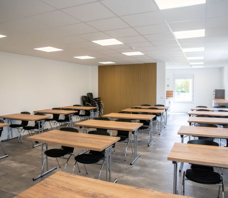 Seminaraum mit Holztischen mit jeweils 2 Stühlen 3er Reihen
