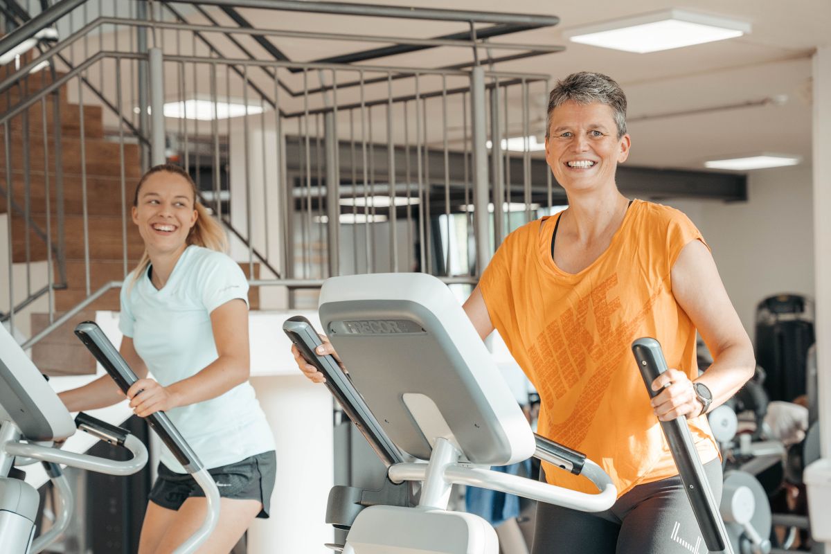 2 Mitgliederinnen trainieren gemeinsam auf den Crosstrainer und haben Spaß