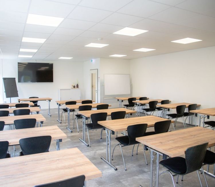 Seminaraum mit Holztischen mit jeweils 2 Stühlen 3er Reihen