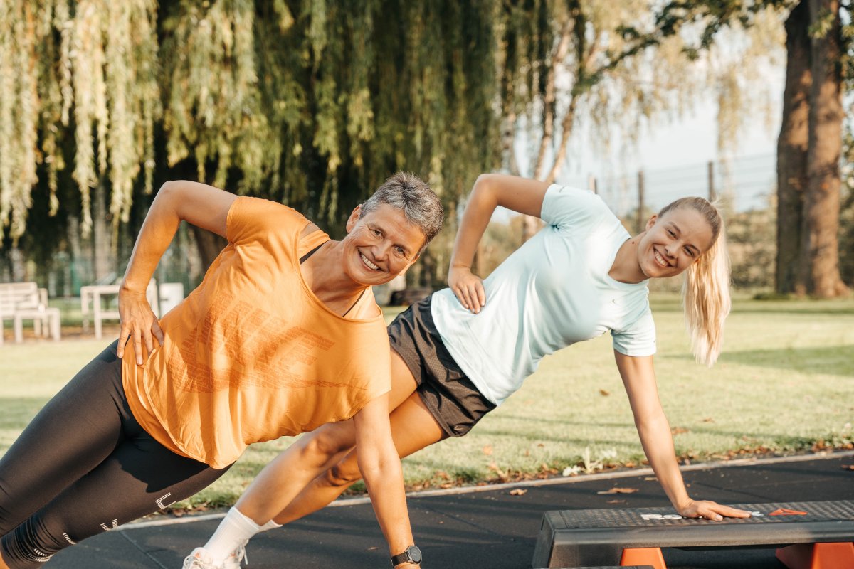 2 Mitgliederinnen trainieren gemeinsam im Outdoor Fitnesspark - Übung: Seitstütz